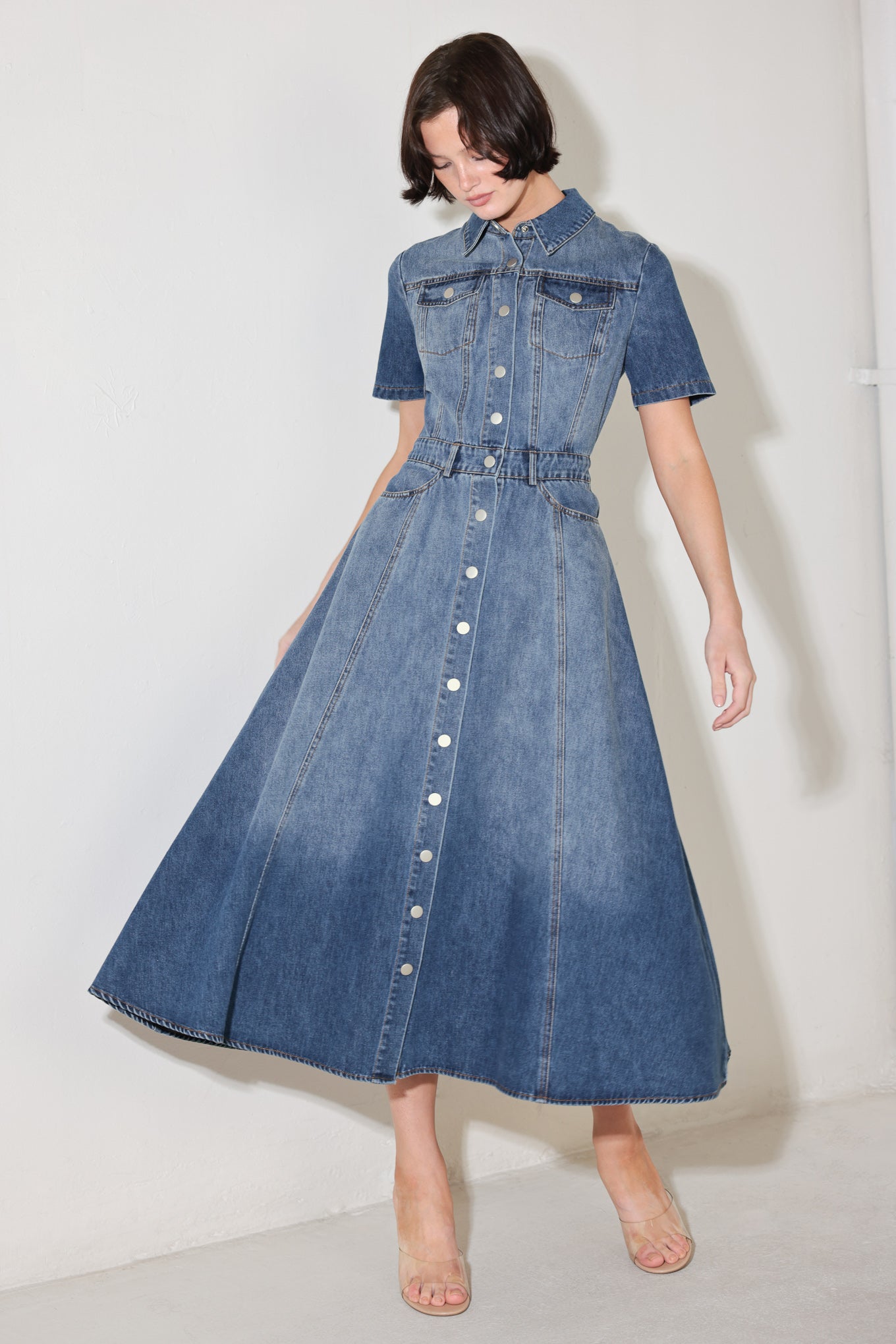 Woman wearing a blue denim dress against a white background
