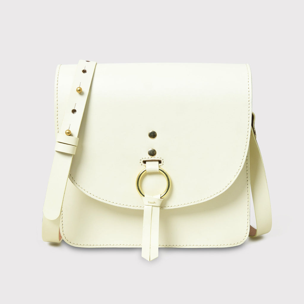 Cream-colored handbag with a gold ring on a light gray background