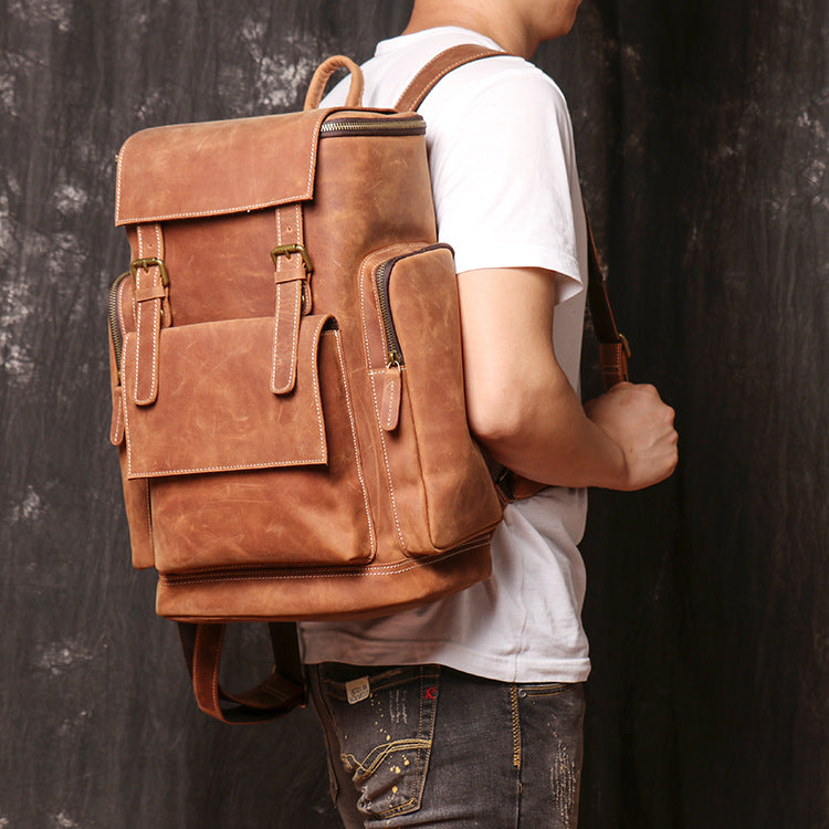 Person wearing a brown leather backpack against a dark background