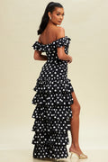 Woman wearing a black polka dot dress with ruffles on a beige background