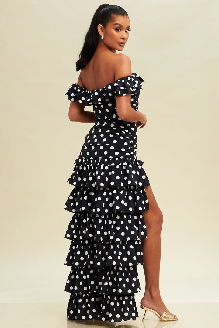 Woman wearing a black polka dot dress with ruffles on a beige background
