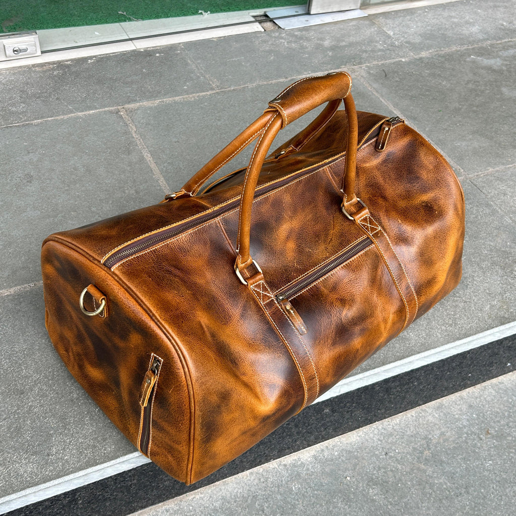 Brown leather duffel bag on a gray pavement