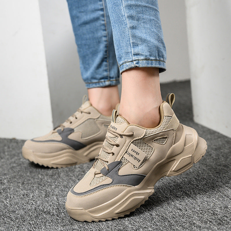 Beige sneakers worn with blue jeans on a gray floor.