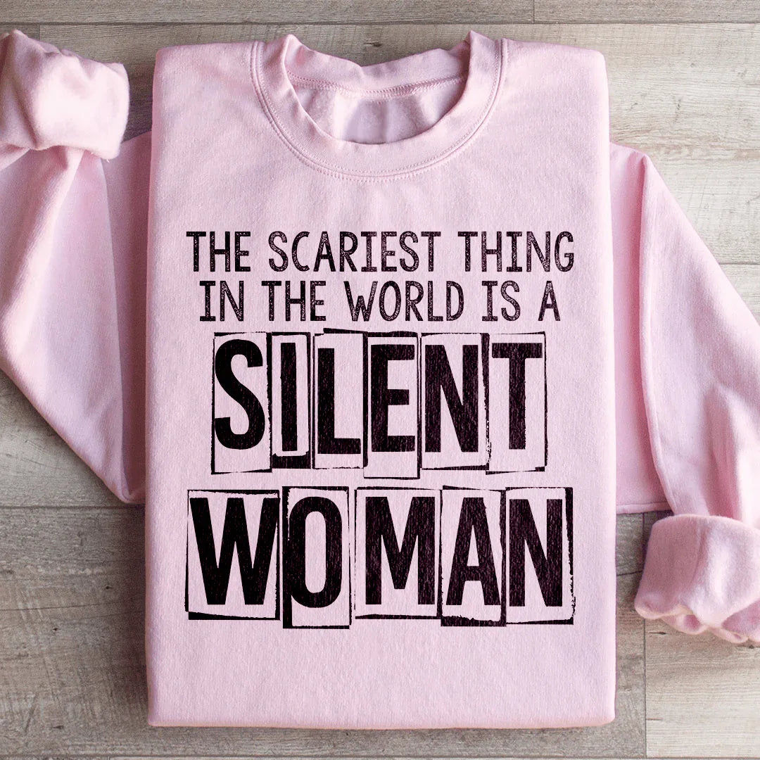 Pink sweatshirt with text 'The scariest thing in the world is a silent woman' on a wooden surface