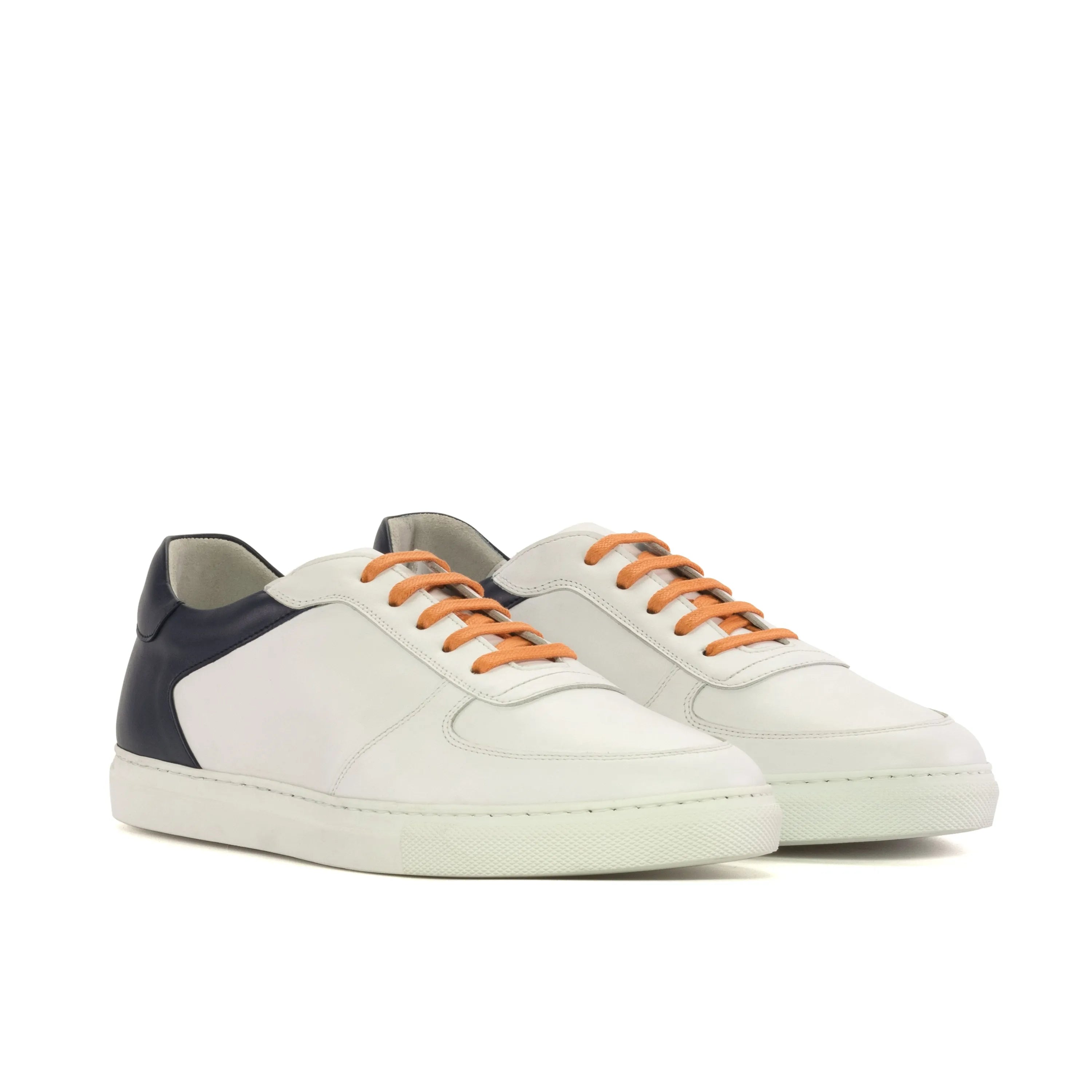 White sneakers with orange laces on a white background